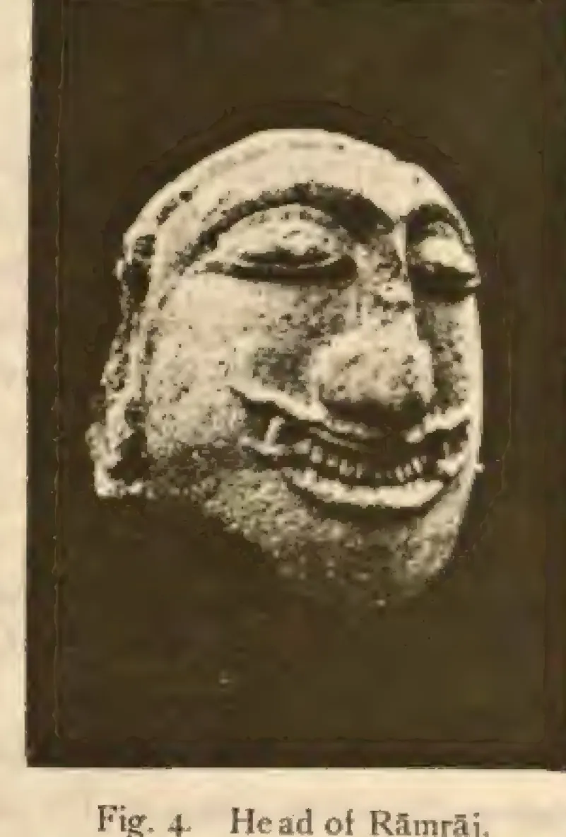 Photograph of a carved stone head with heavy-lidded eyes and a broad grimacing mouth showing teeth, against a dark background.