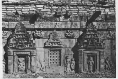 Old photograph of a temple wall with niches holding figure sculptures and a pierced stone window, above a moulded base.