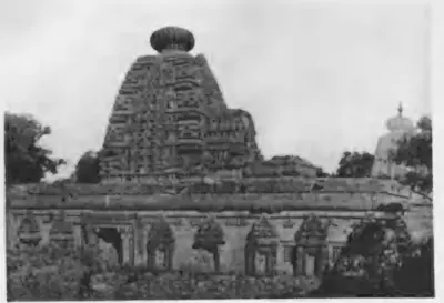 Old photograph of a temple with a tall curved tower crowned by a round ribbed stone and a long wall of carved niches.