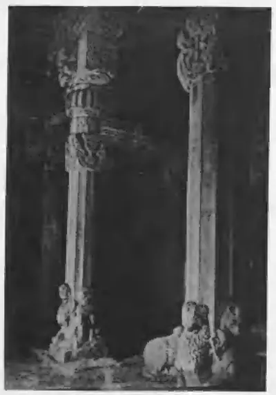 Old photograph of slender pillars in a dark temple interior, with sculptures lying on the floor at their bases.