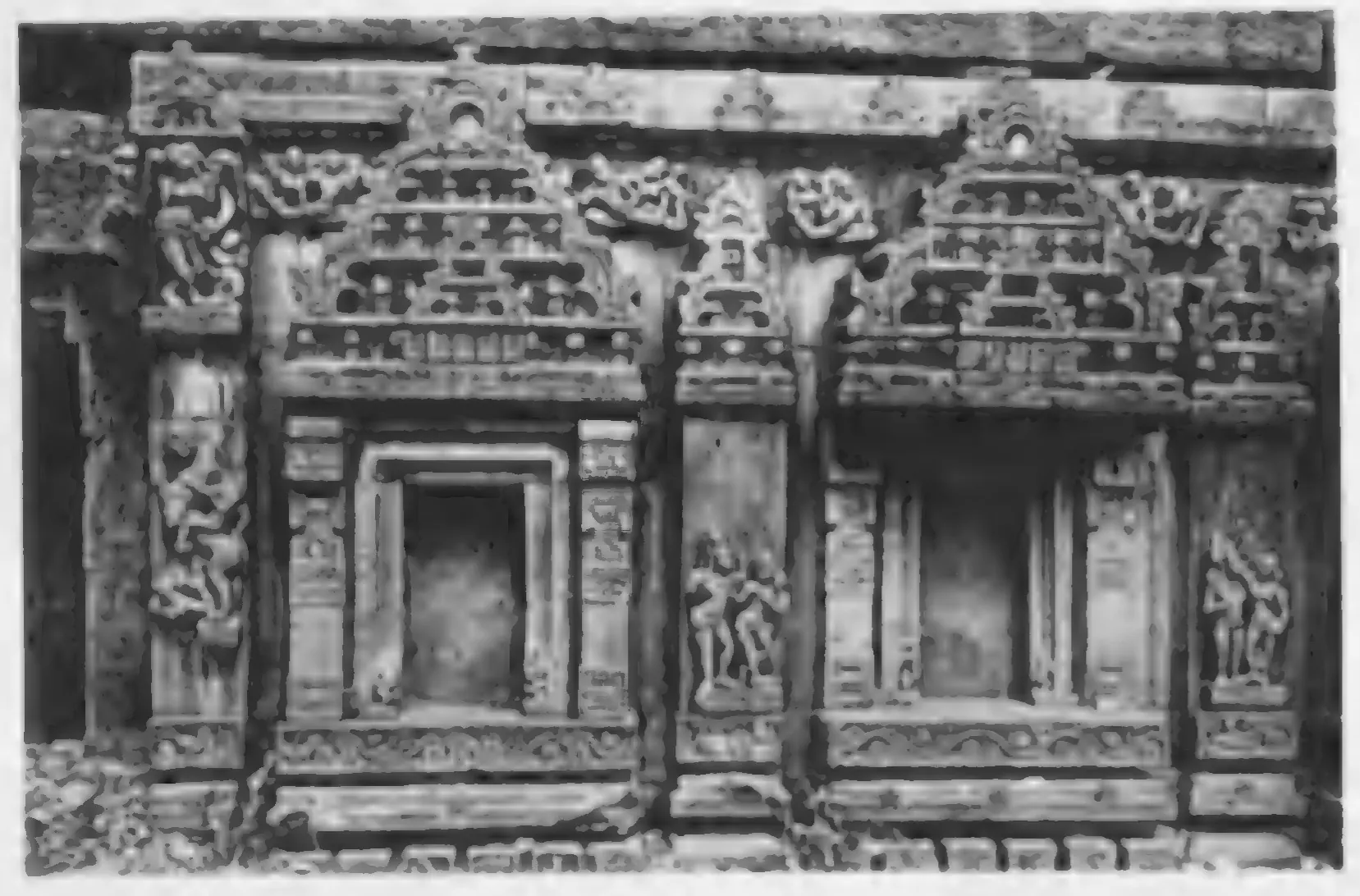 Old photograph of the carved outer wall of a temple: niches framed by pilasters and arched pediments.