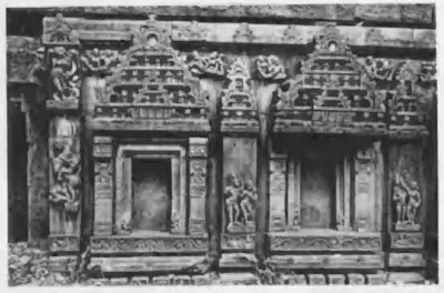Old photograph of the carved outer wall of a temple: niches framed by pilasters and arched pediments.