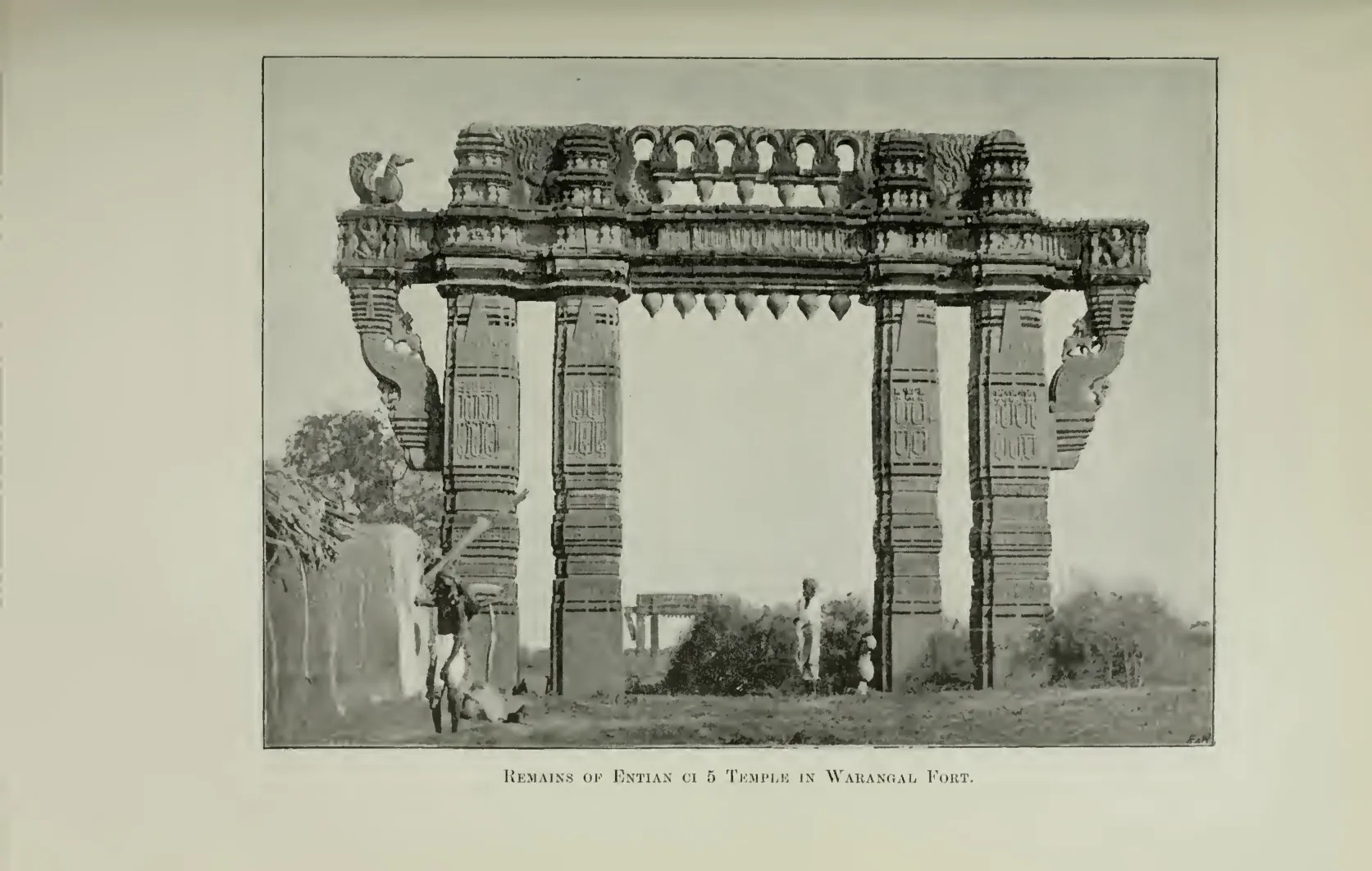 Photograph of a tall carved stone gateway (torana) standing among ruins inside Warangal fort. Printed sideways.