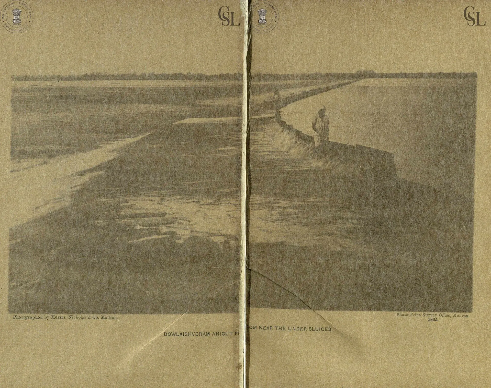 Photograph of the long masonry anicut across the Godavari at Dowlaishweram, water spilling over it, with a man standing on the work; printed across two pages.