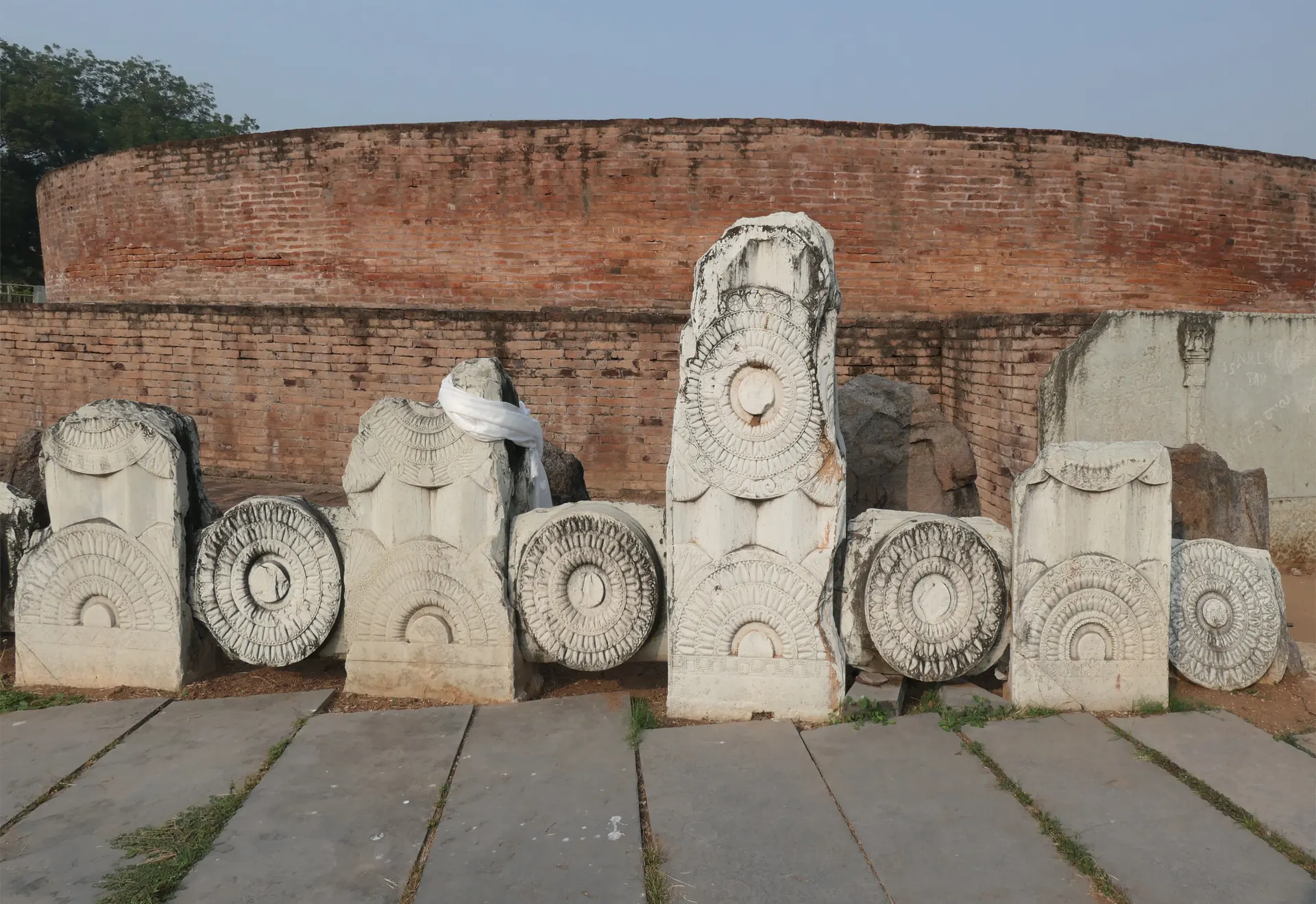 Re-erected carved limestone railing pillars and roundels in front of the brick drum of the Amaravati Mahachaitya stupa.