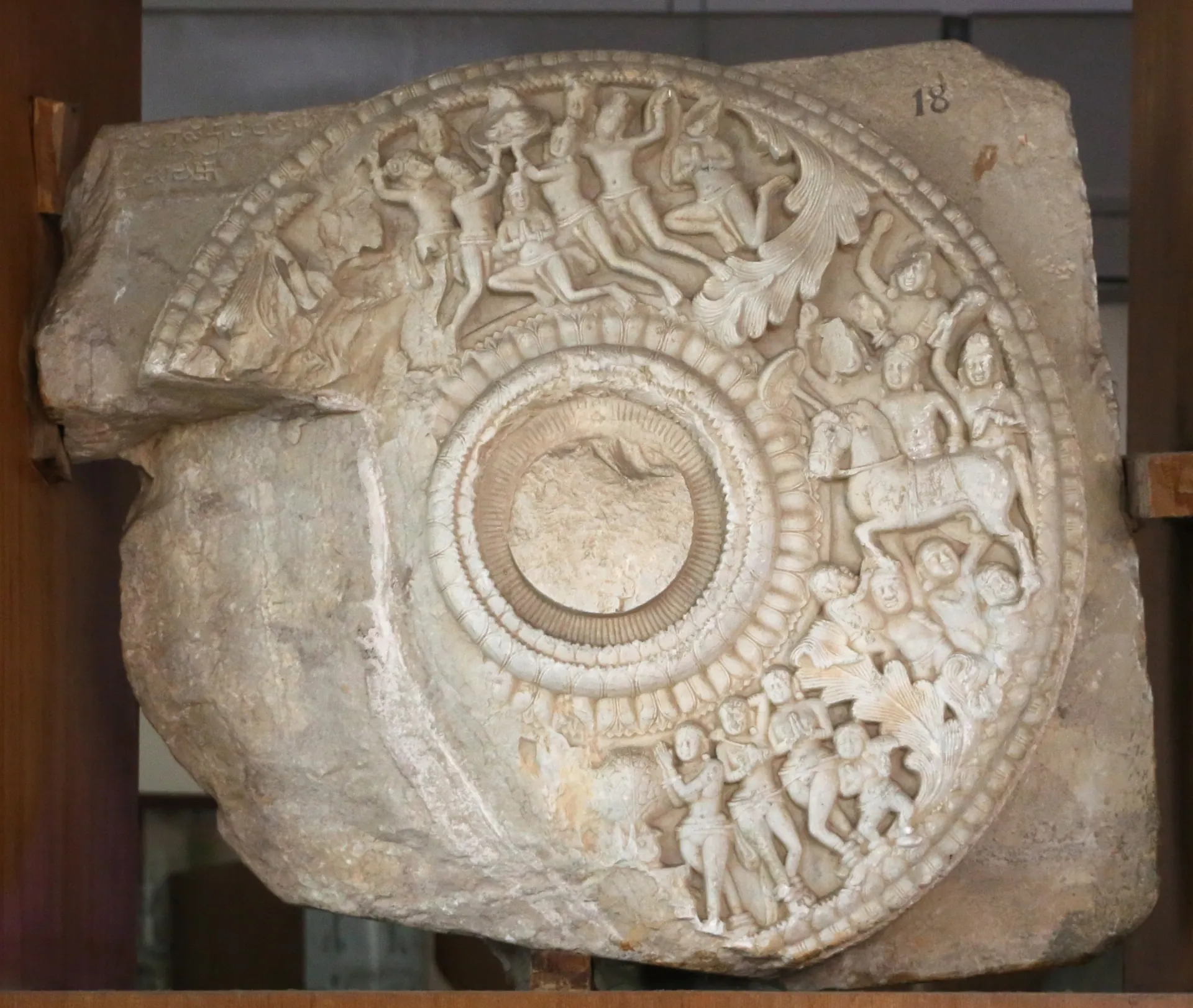 Carved limestone roundel from the Amaravati stupa, c. 150 CE, with crowded narrative relief around a central lotus, in the Government Museum, Chennai.