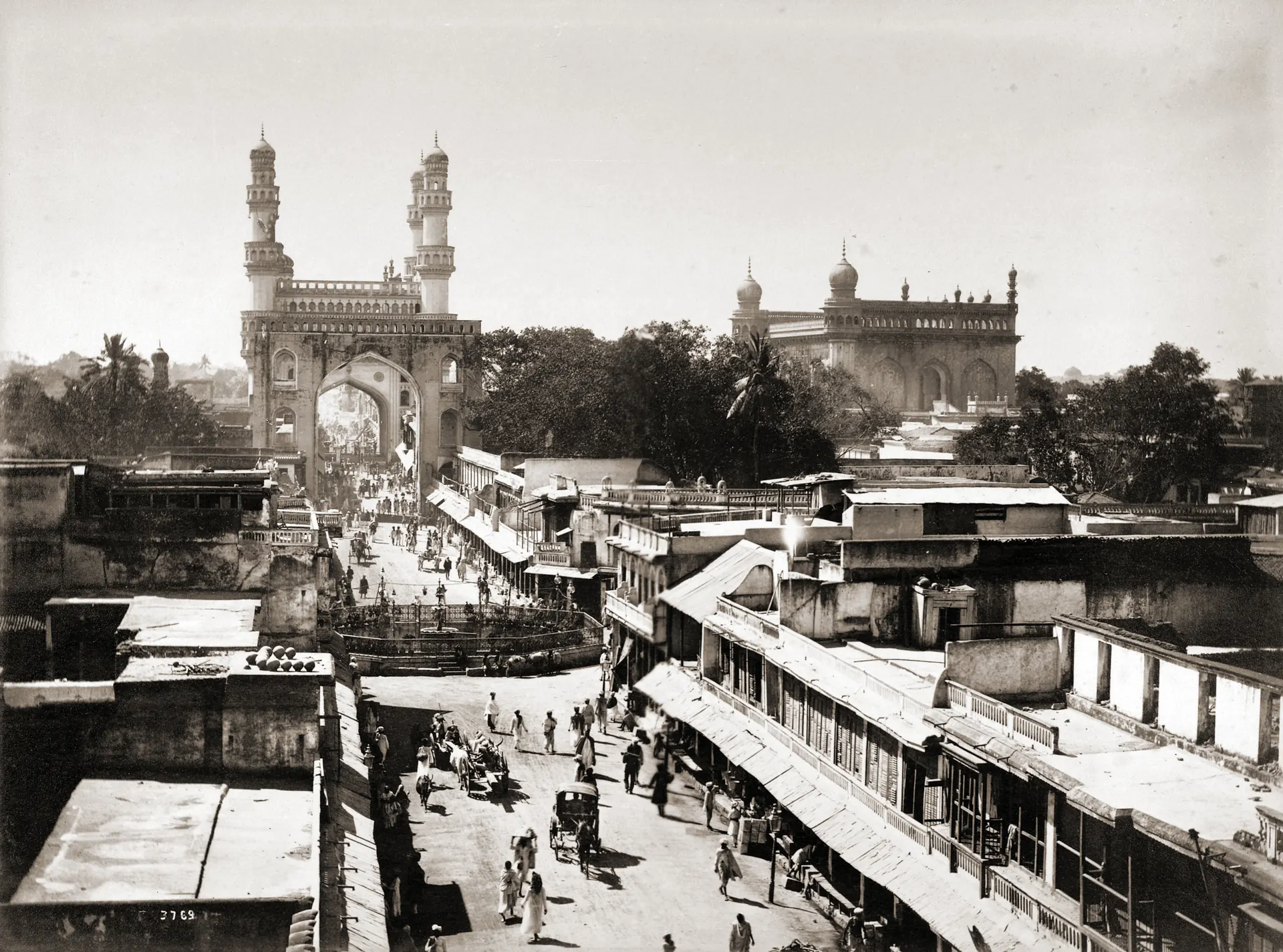 1880s photograph of a busy street in Hyderabad leading to the Charminar, with the Mecca Masjid on the right.