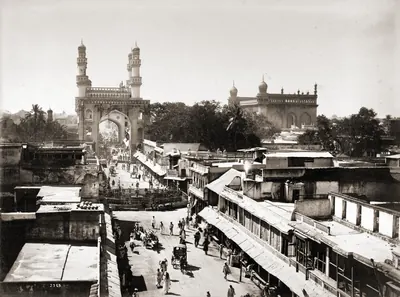 1880s photograph of a busy street in Hyderabad leading to the Charminar, with the Mecca Masjid on the right.