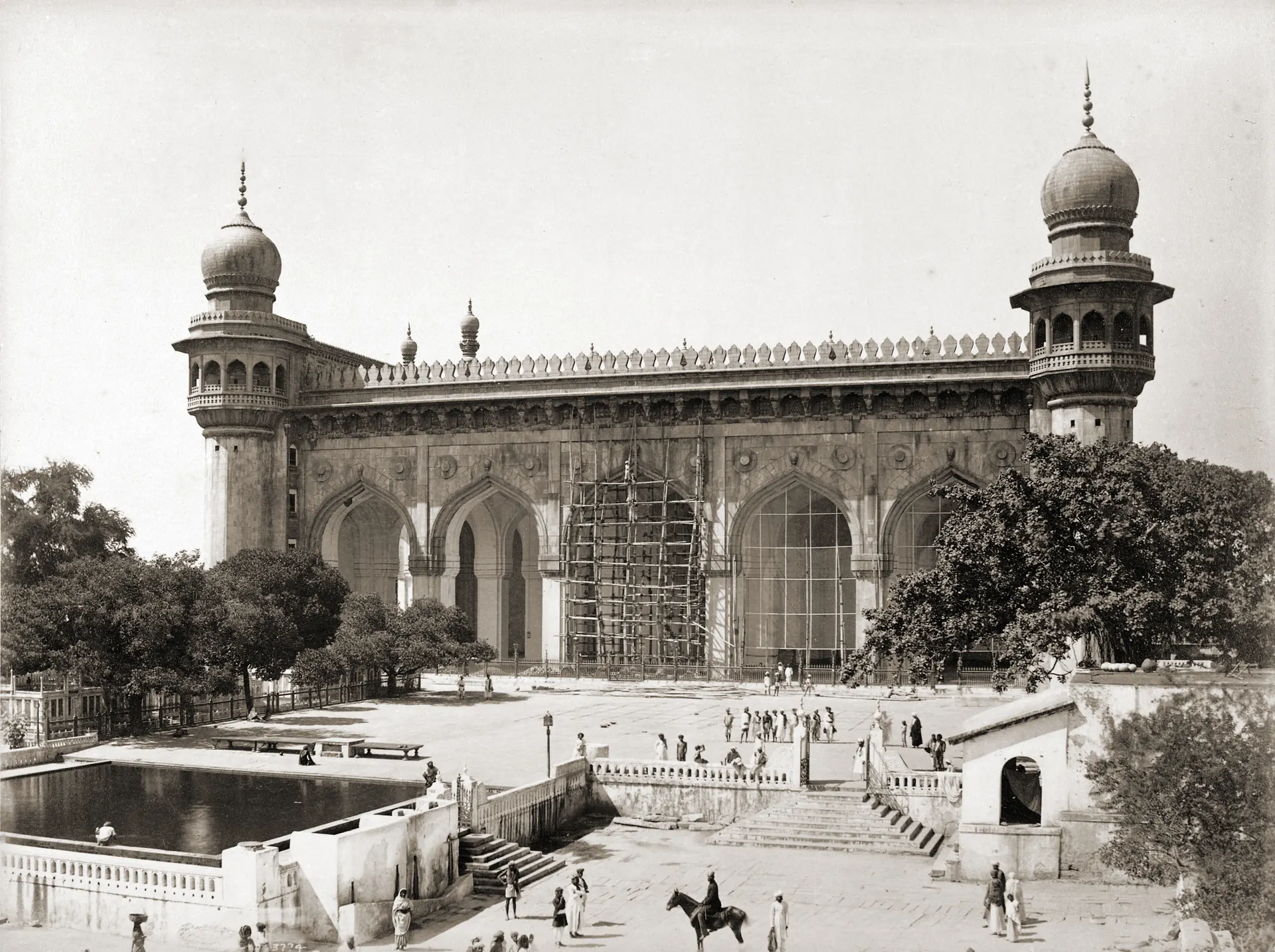 1880s photograph of the granite facade of the Mecca Masjid in Hyderabad, partly under scaffolding.