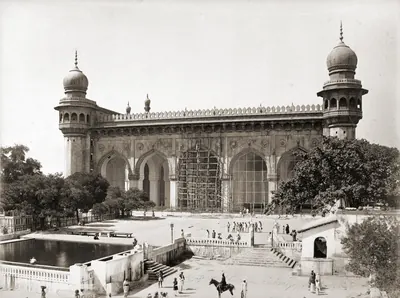 1880s photograph of the granite facade of the Mecca Masjid in Hyderabad, partly under scaffolding.