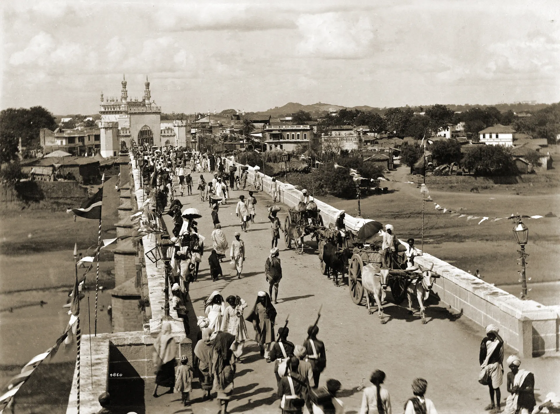1880s photograph of crowds and carts crossing a bridge at the entrance to Hyderabad city.