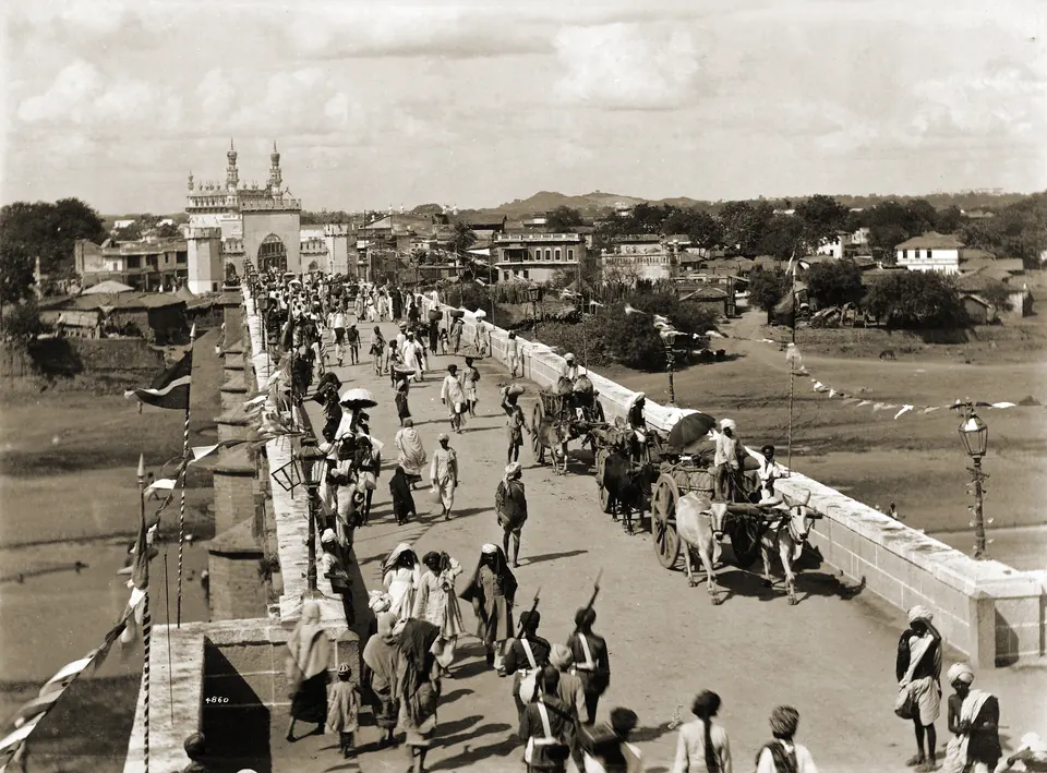 1880s photograph of crowds and carts crossing a bridge at the entrance to Hyderabad city.