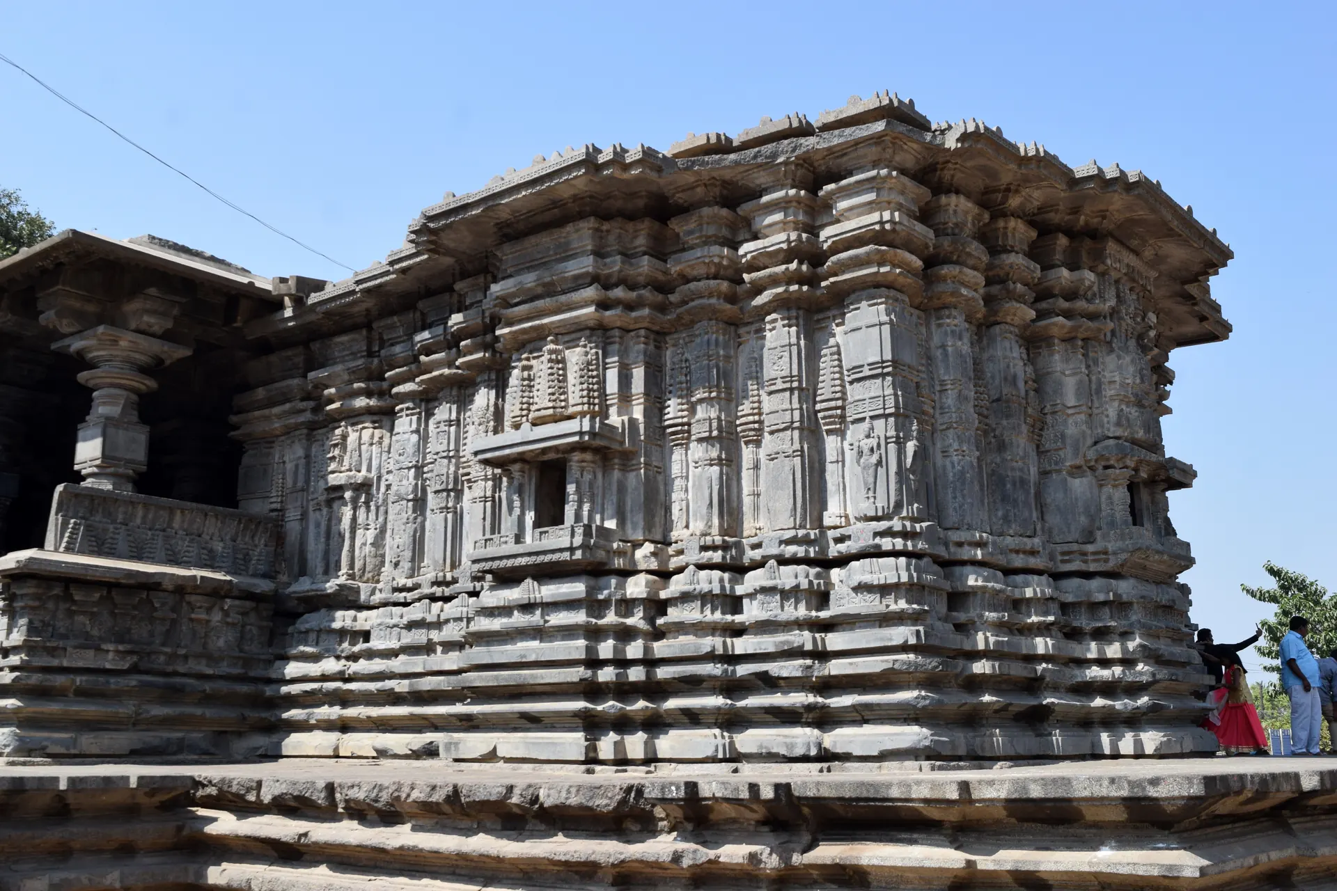 Exterior of the Thousand Pillar Temple at Hanamkonda, with the stepped, deeply carved black basalt walls of a shrine under a blue sky.
