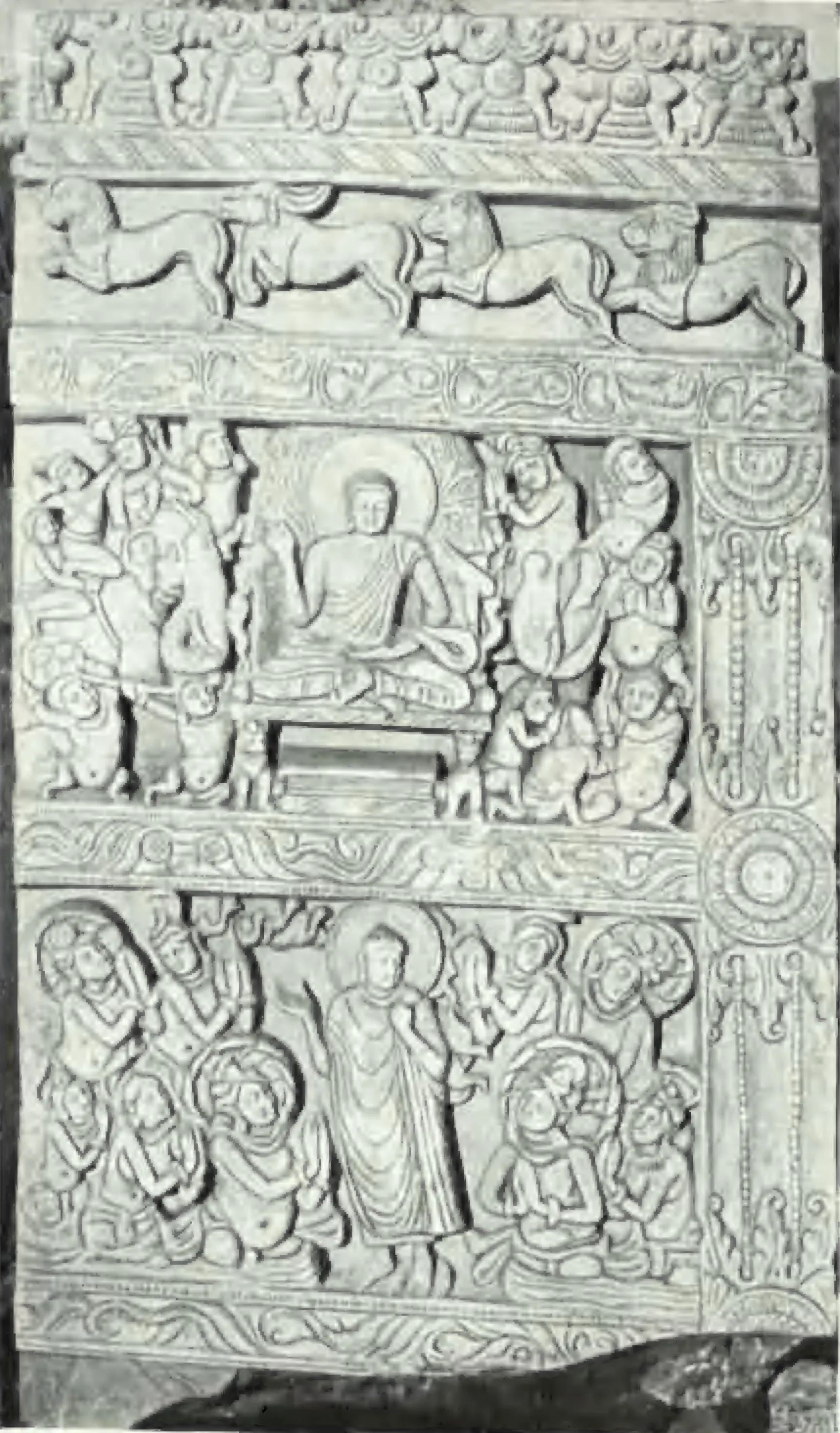 A carved limestone slab in registers: a frieze of running animals above, a seated Buddha among worshippers in the middle and a standing Buddha among figures below.