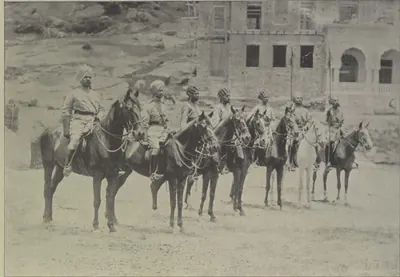 A line of mounted lancers in uniform, with a building behind.
