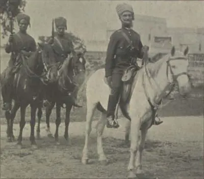 Three mounted policemen in uniform, one on a white horse.