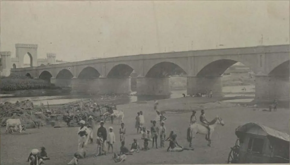 The Afzal bridge, with its row of arches, over the Musi river, with people in the river bed.