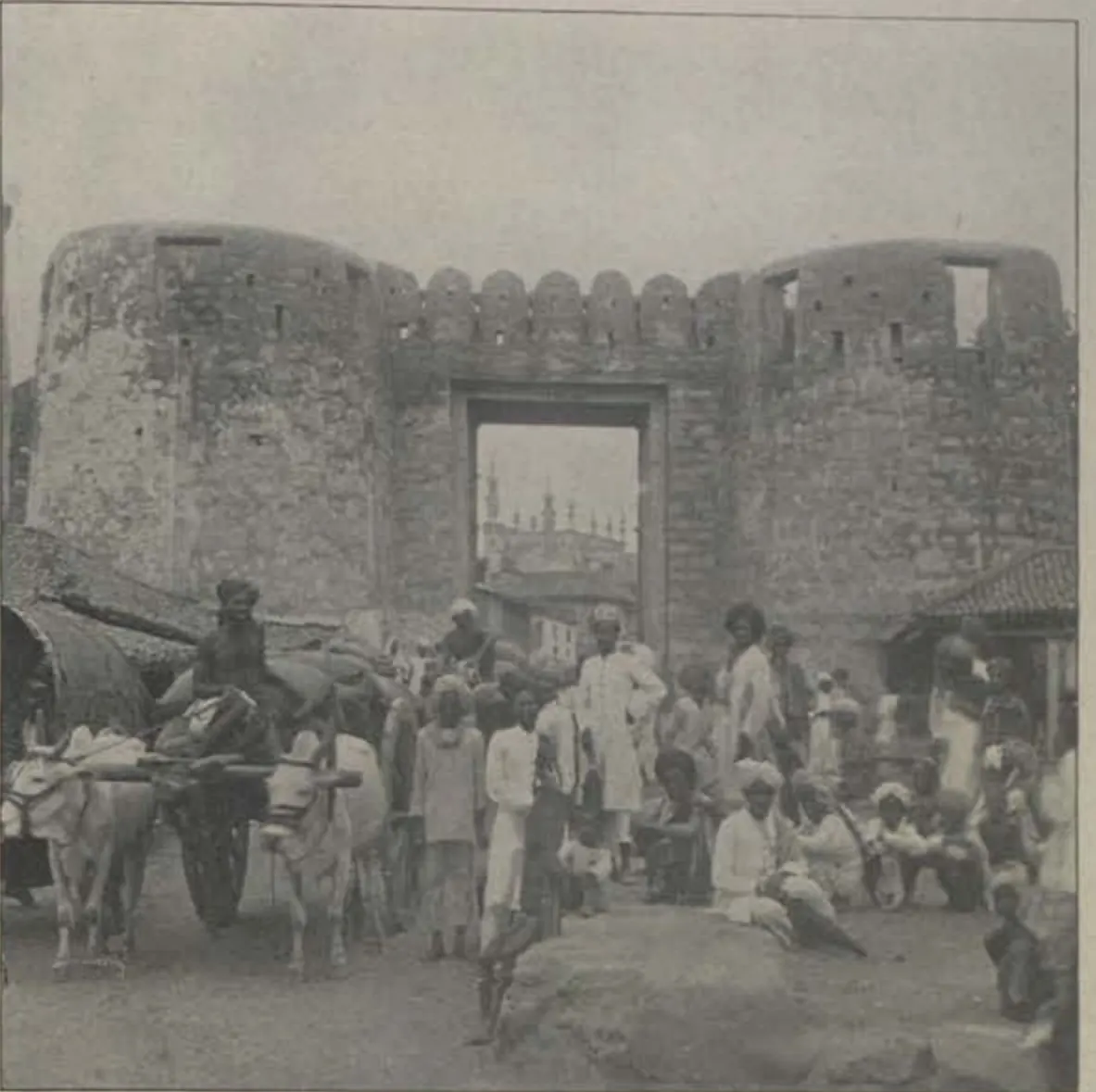 The Delhi Gate, a gateway between round bastions, with a crowd and carts in front.
