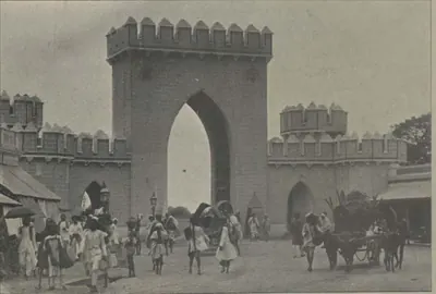 The Afzal Gate, a tall pointed arch between crenellated walls, with people and carts.