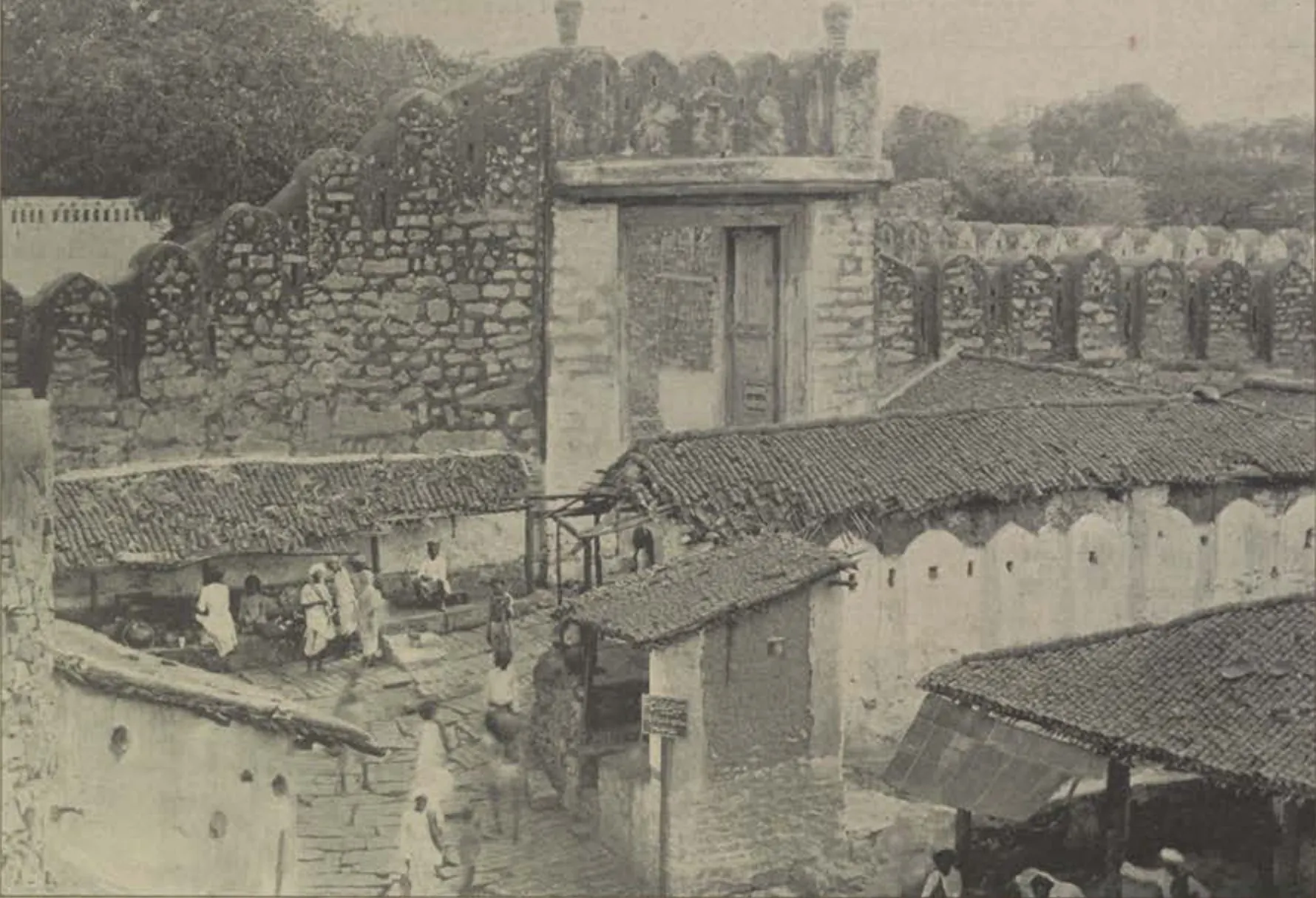 The Champa Gate among old walls and tiled houses.