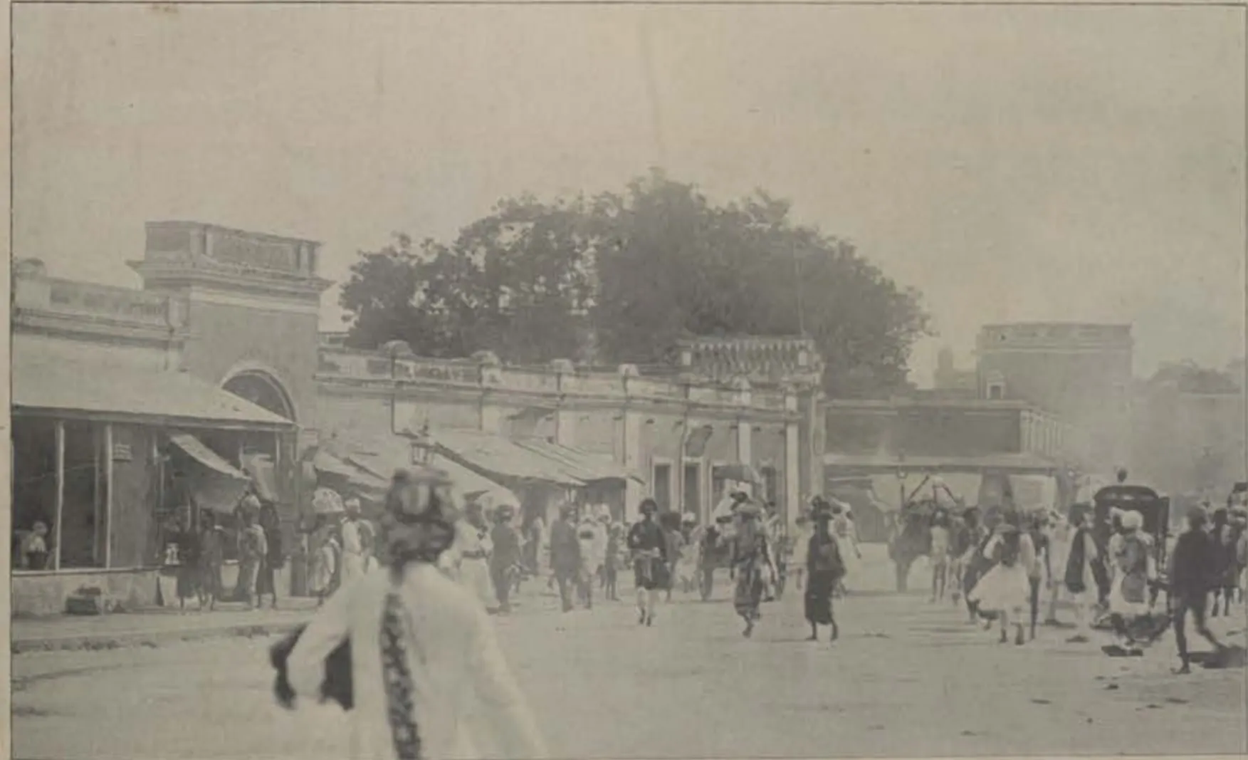 A busy main street of Hyderabad, with people walking and buildings on each side.