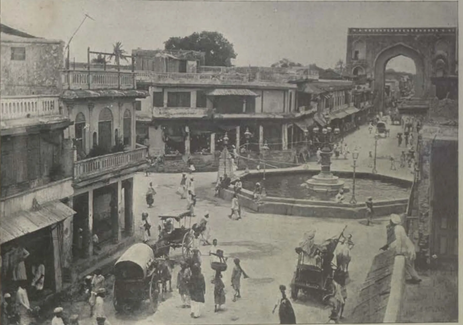 The Gulzar Hauz, a fountain basin in a square, with buildings, people and carriages around it.