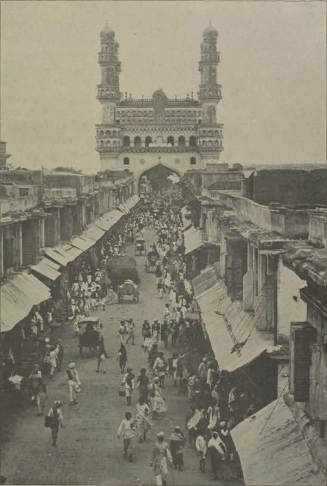 The Charminar in Hyderabad, its four minarets rising above the arched central block, with a street in front.