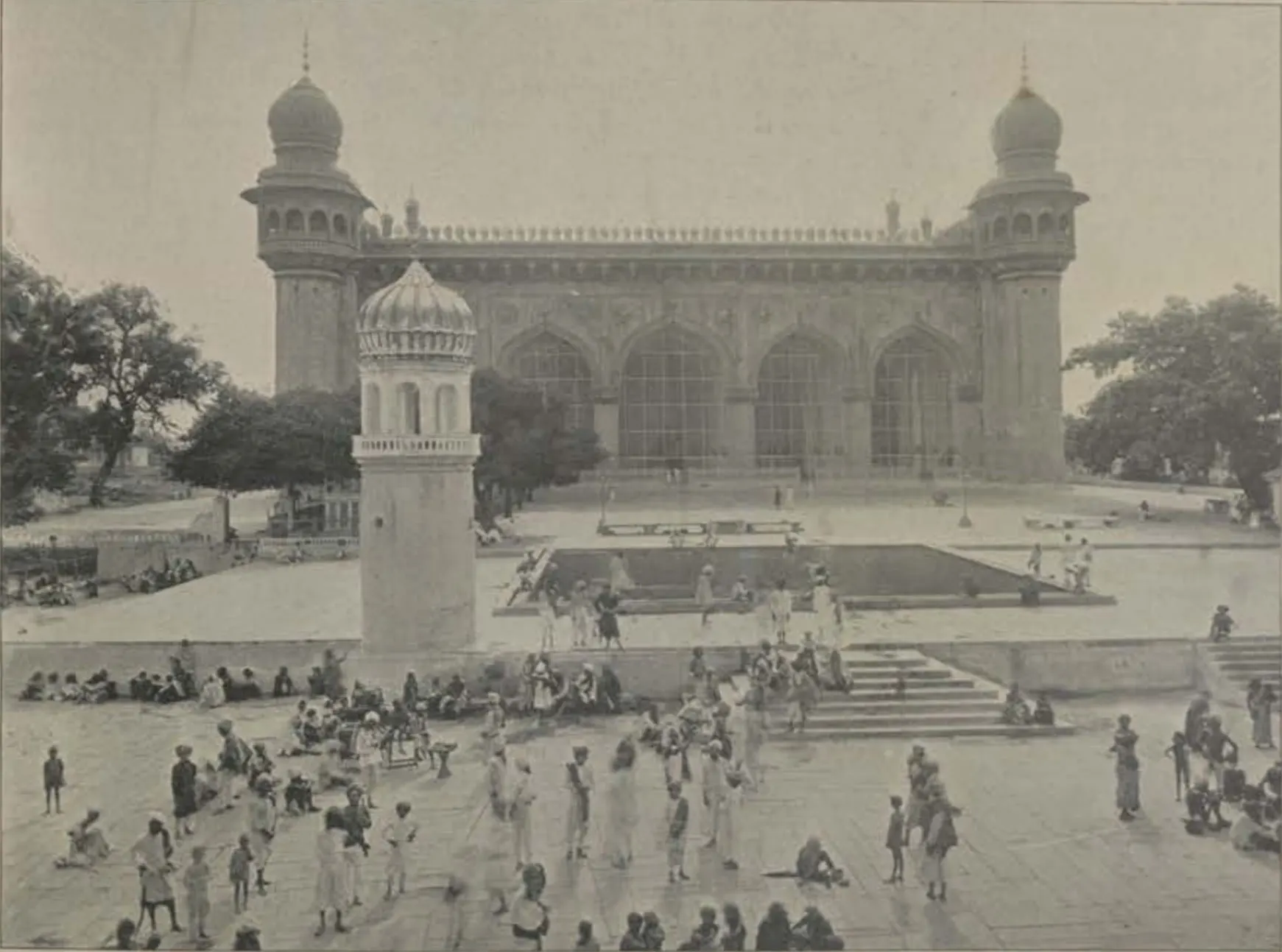 The Mecca Masjid of Hyderabad, its large arched facade with corner minarets, seen across the courtyard.