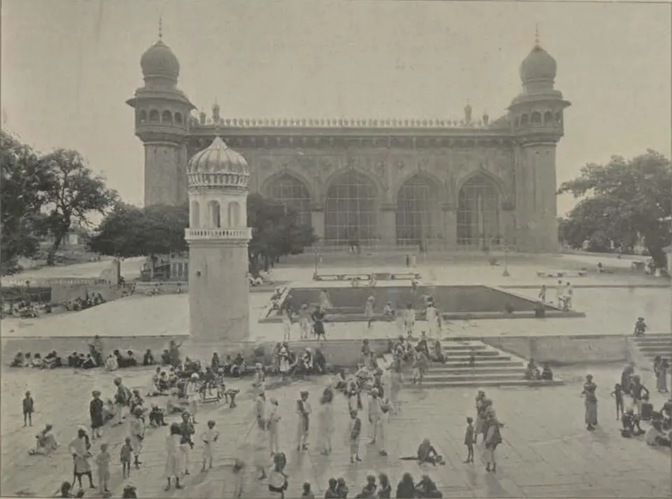 The Mecca Masjid of Hyderabad, its large arched facade with corner minarets, seen across the courtyard.