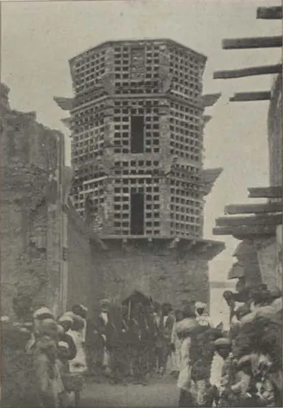 A tall latticed pigeon tower above a crowd of people.