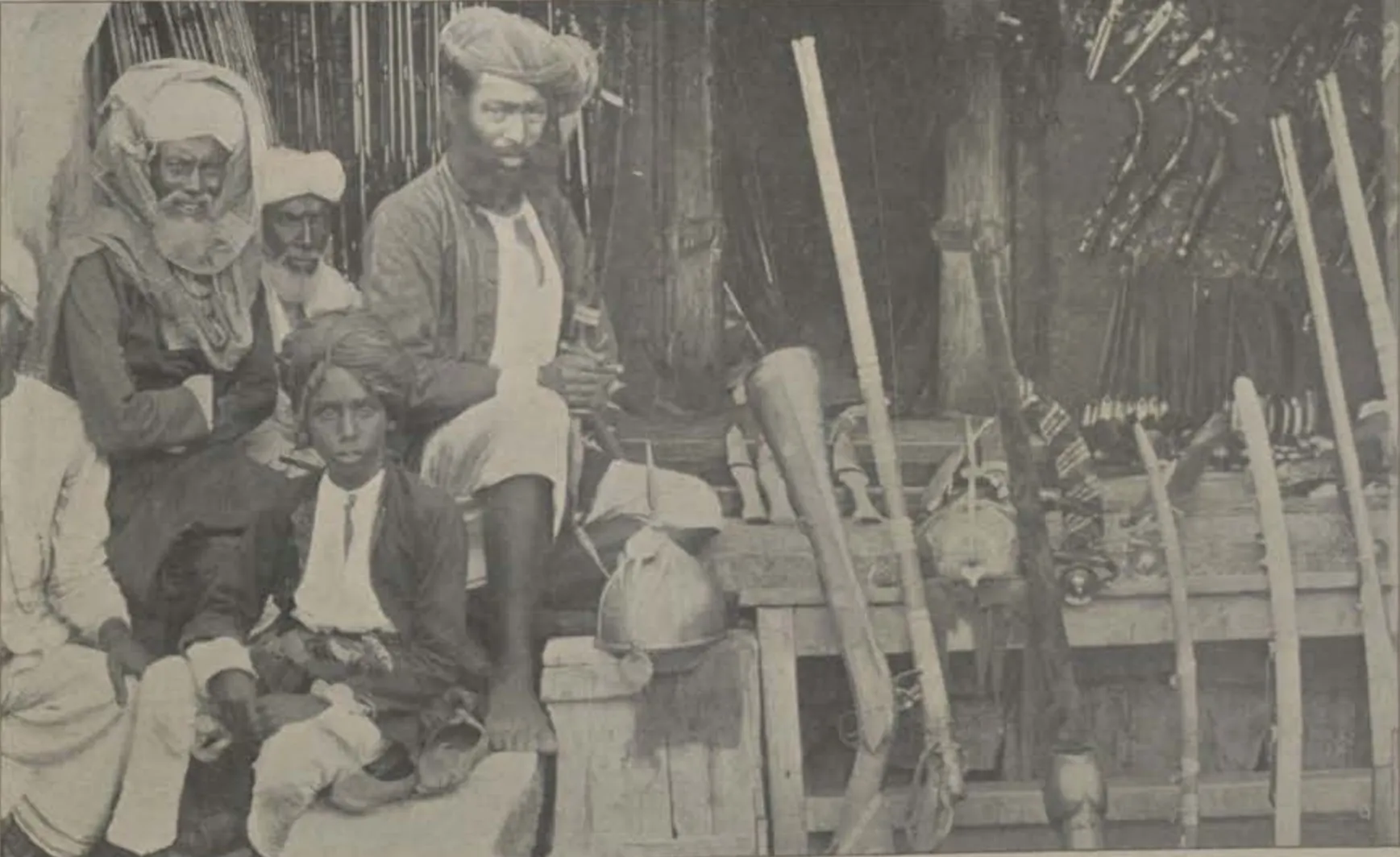 Men seated with weapons in the arms bazaar.