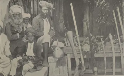 Men seated with weapons in the arms bazaar.