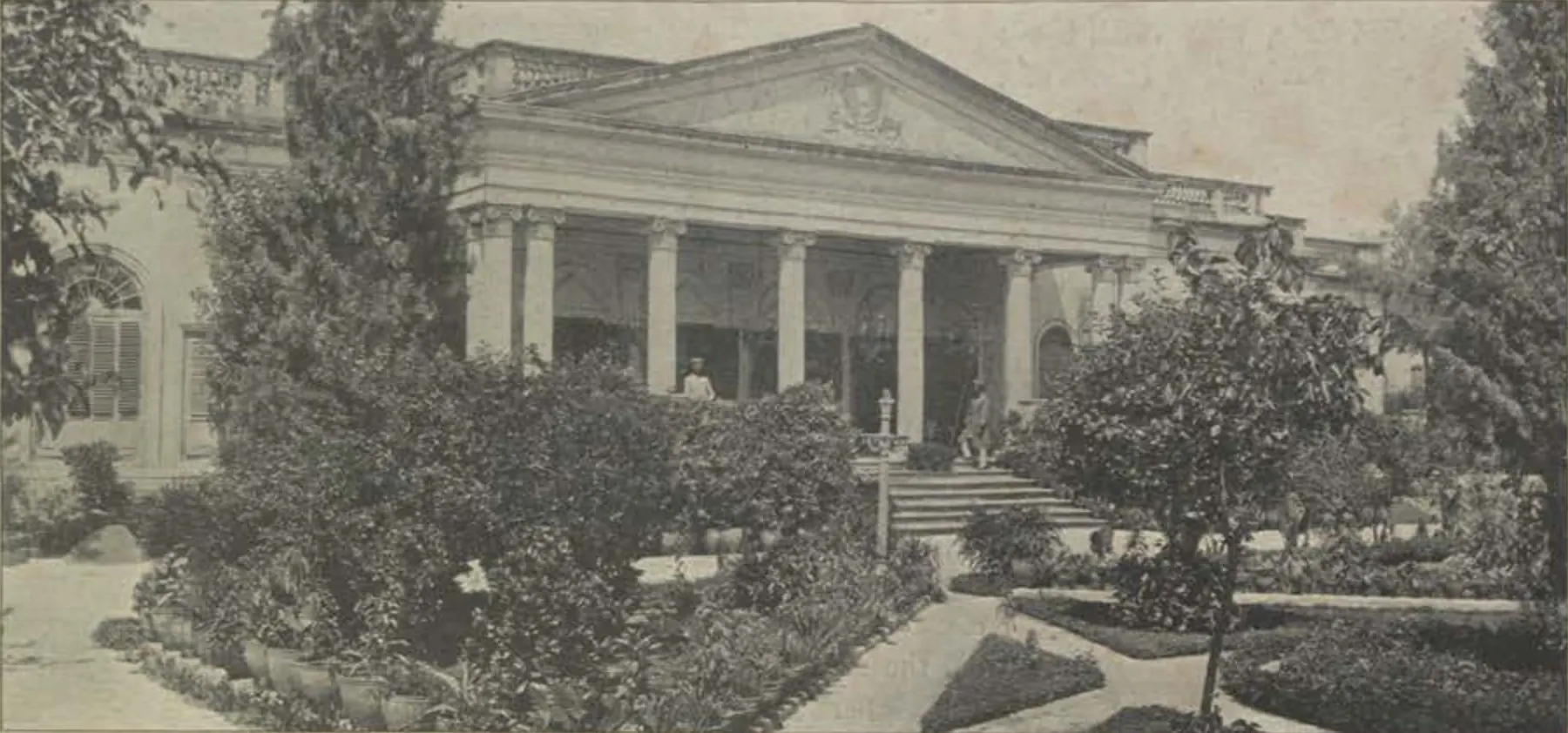 A classical palace front with columns, seen behind a garden.