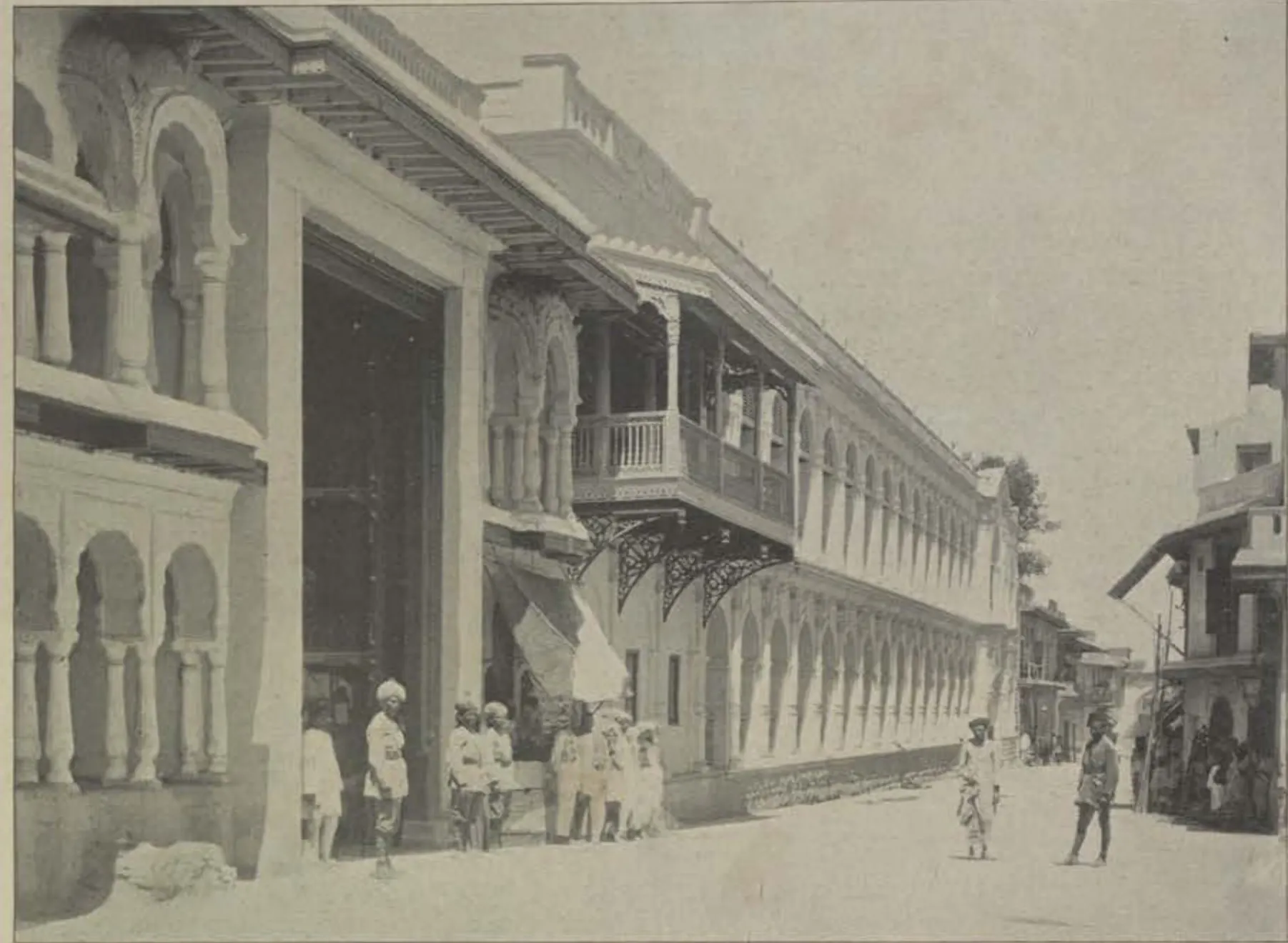 A long many-storeyed palace with balconies along a street.