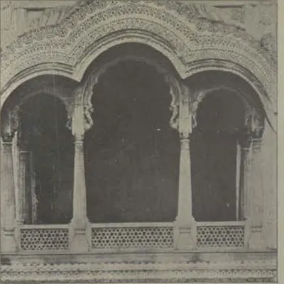 A carved balcony window with cusped arches and a lattice parapet.