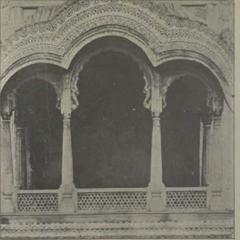 A carved balcony window with cusped arches and a lattice parapet.