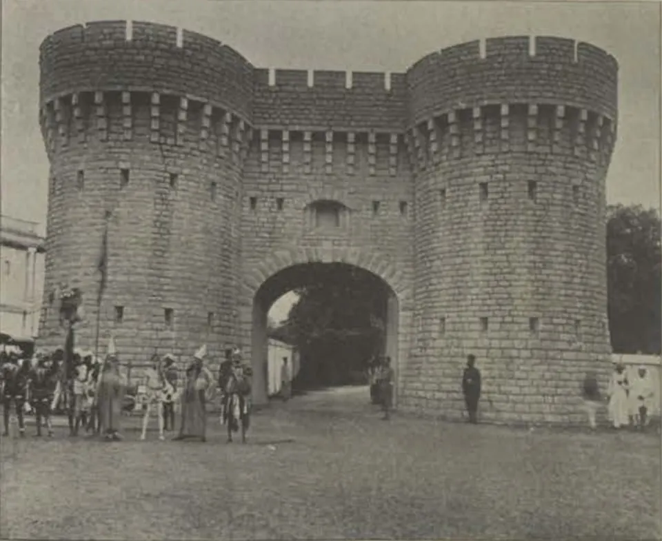 The Residency gate, a castellated gateway between two round towers, with people in front.