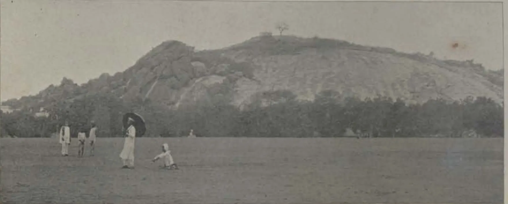The Black Rocks, a rocky hill beyond an open field with people.