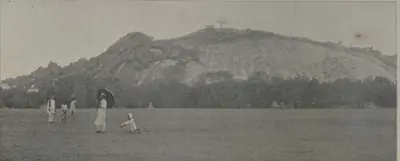 The Black Rocks, a rocky hill beyond an open field with people.