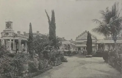 Shapur Wadi, buildings along a garden path with palms and cypresses.