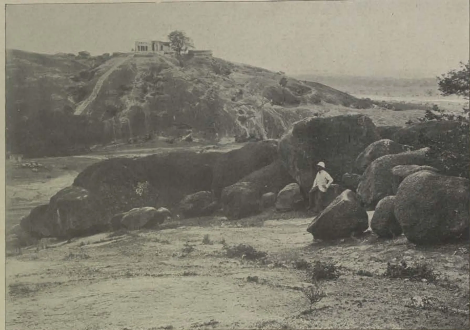 Rocky ground and a hill with a building on its top.