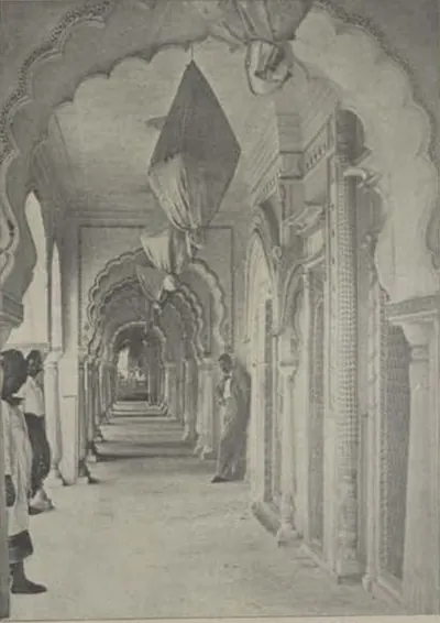 A long marble arcade of cusped arches in the Shams-ul-Umara tombs, with people standing in it.