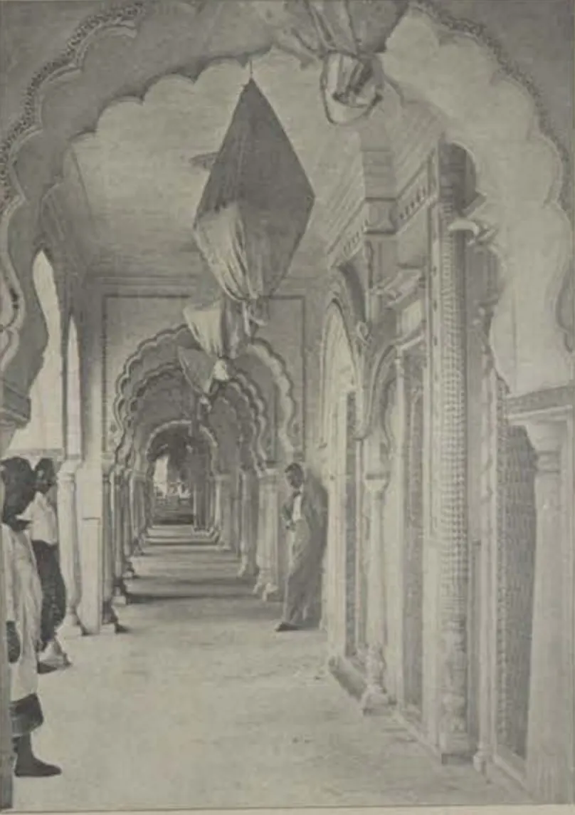 A long marble arcade of cusped arches in the Shams-ul-Umara tombs, with people standing in it.