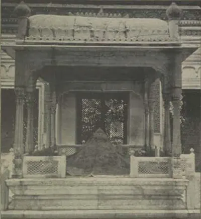 A carved marble canopy with lattice screens over a grave.