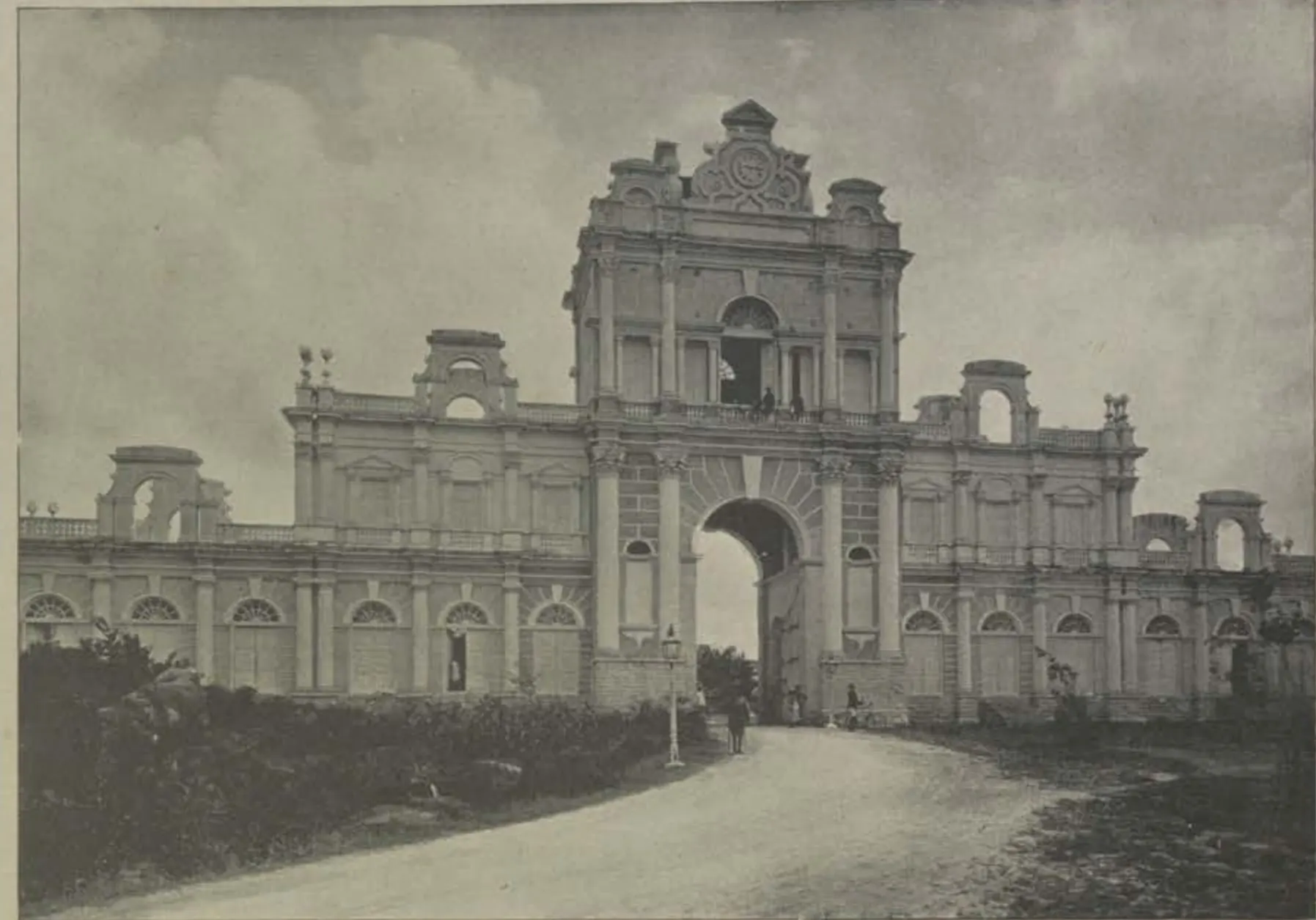 The gateway of the Falaknuma palace, a tall ornate arch with a road through it.