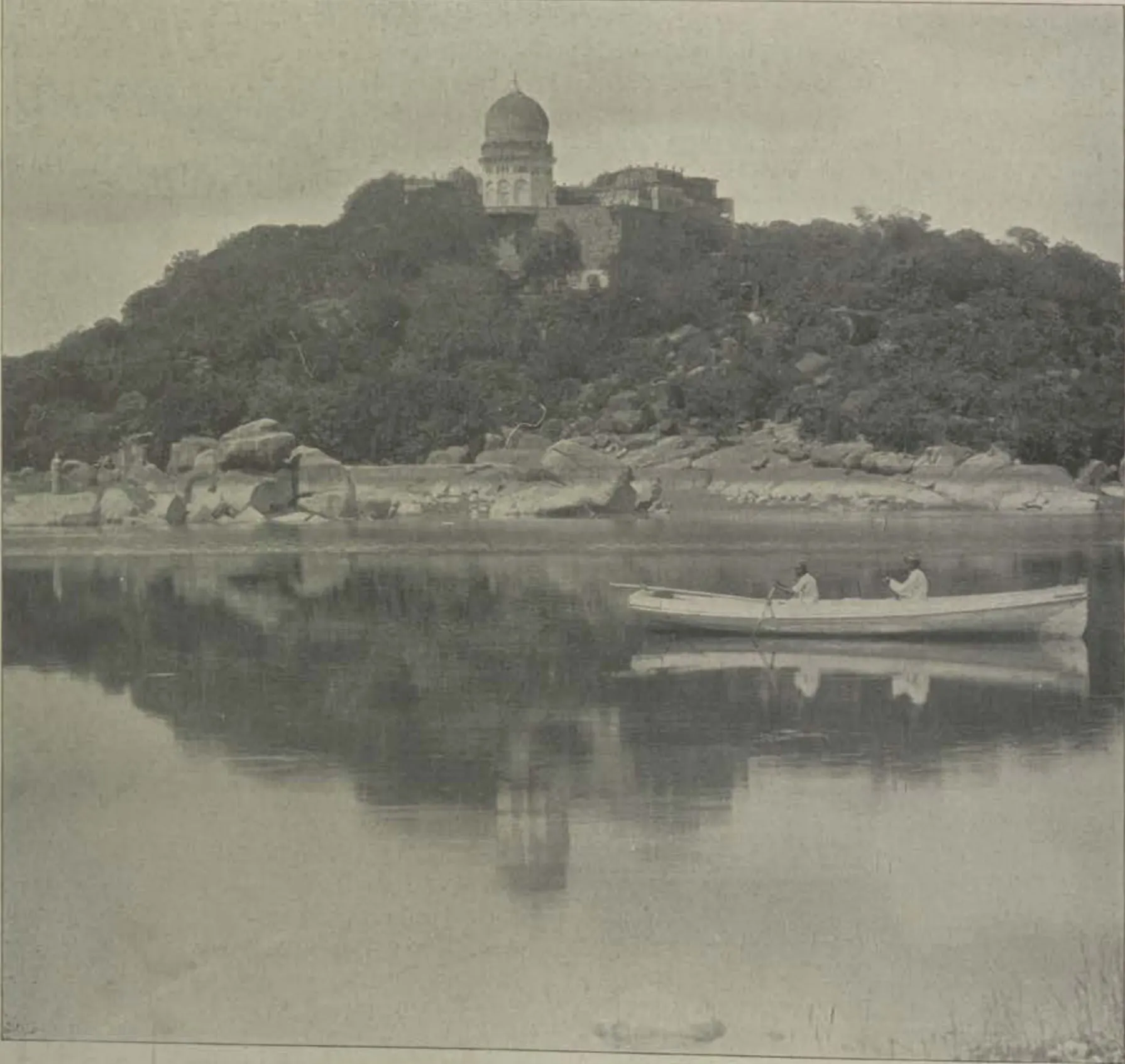 A domed tomb on a hill above the Mir Alam lake, with a boat on the water.