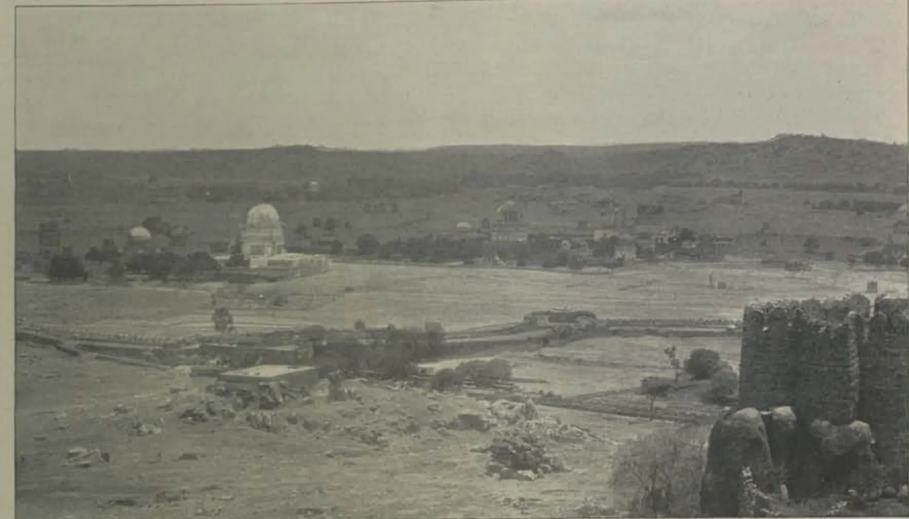 A view from the citadel towards a domed tomb on the plain, with a bastion at right.