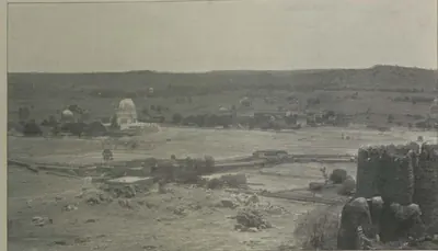 A view from the citadel towards a domed tomb on the plain, with a bastion at right.