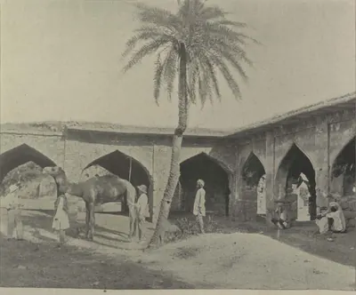 The arcaded court of the caravanserai, with a camel, men and a palm tree.