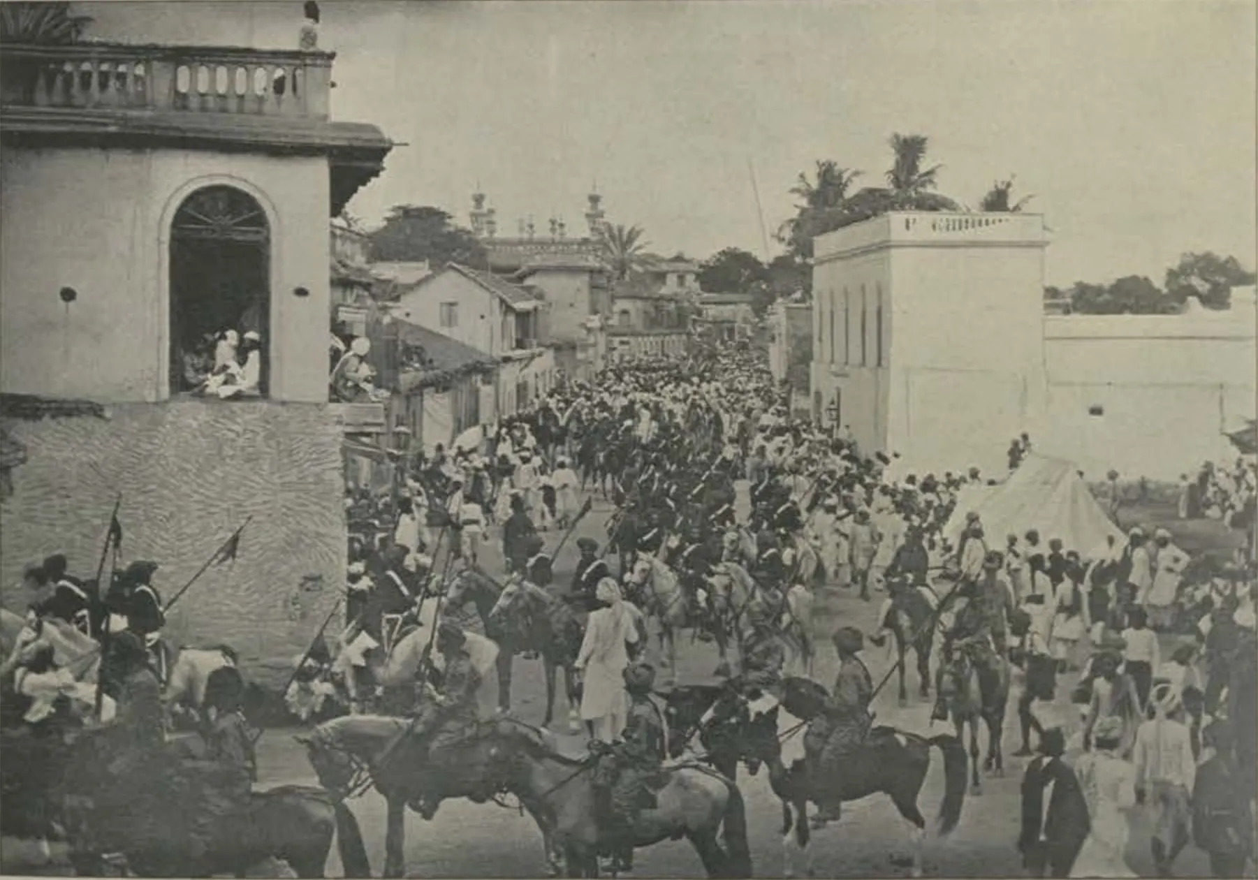Horsemen riding in a crowded street procession.